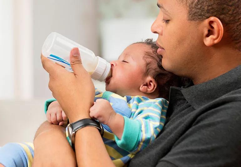 parent feeds baby bottle